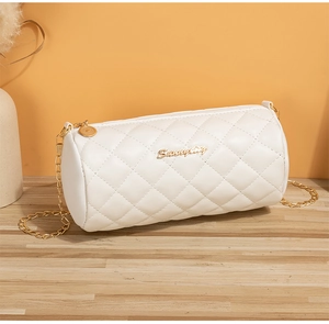 Detail of white quilted barrel bag with gold chain strap and metallic logo on wooden desk