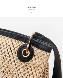 Detailed close-up of straw woven tote showing black leather trim and golden ring hardware