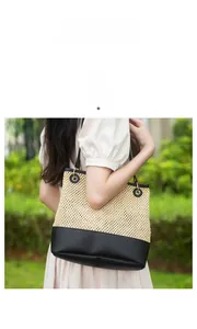 Detail of woven straw tote bag featuring black leather contrast bottom and sturdy handles