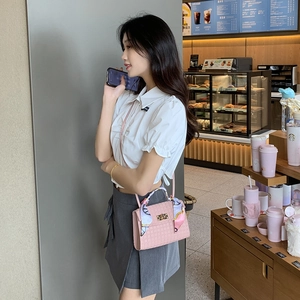 Rosa Handtasche mit geprägtem Leder und Seidentuch in Café-Atmosphäre