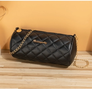 Detail view of black quilted cylinder bag with gold chain strap and PU leather texture