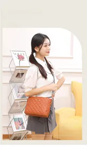 Close-up of brown quilted shoulder bag with patterned wide strap on a model