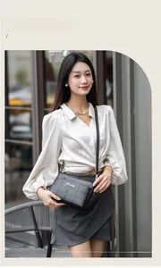 Close-up of black quilted crossbody bag with metal logo on a street style model