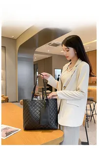 Sac cabas matelassé avec pochette assortie porté par un mannequin dans un café
