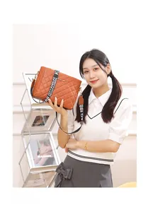 Detail shot of brown quilted crossbody bag with stylish patterned wide shoulder strap