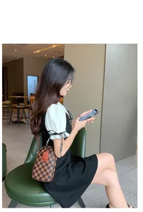 Brown checkered mini crossbody phone bag shown on a model in a cozy cafe setting