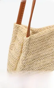 Détail du tissage en chevrons beige et de la bandoulière en cuir marron du sac