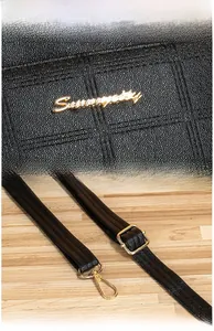 Detail of black pebbled leather bag with gold Serenity logo and polished metal buckle