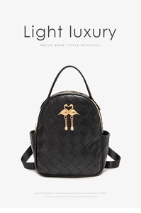 Close-up of black quilted backpack with golden swan buckle and delicate fringe detail