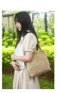 Close-up of woven straw tote bag with leather shoulder straps in an outdoor natural setting