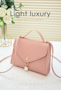 Detail of pink embossed crossbody bag with pearl charm and golden hardware accent