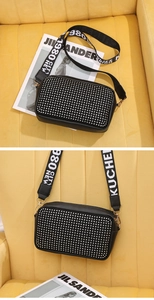 Détail du sac bandoulière noir avec clous argentés et une bandoulière en maille