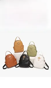 Miniature leather backpacks in five colors with swan charms on white pedestals