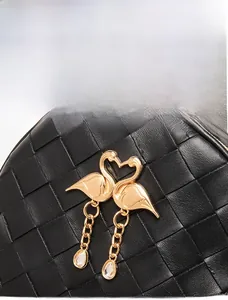 Detail of black quilted leather backpack featuring gold swan charms and elegant tassels