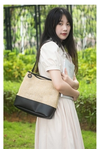 Detail of woven straw tote bag with black leather patchwork and matching shoulder strap