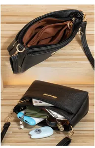 Detail view of multi-pocket crossbody bag with black lychee grain texture and gold zippers