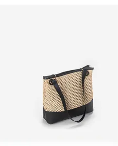 Detail of woven straw texture and black faux leather contrast trim on large tote bag