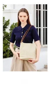 Détail du sac cabas en paille tissé main avec anses en cuir marron sur l'épaule du mannequin