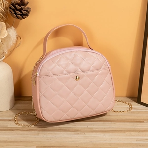 Pink quilted crossbody bag with golden chain and metallic buckle in minimalist setting