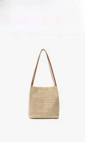 Vue détaillée de la texture du sac cabas en paille et des anses en similicuir marron