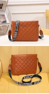 Detail of brown quilted crossbody bag with a stylish wide logo strap and gold hardware