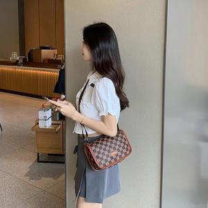 Sac bandoulière marron à damier pour femme avec logo doré en situation réelle