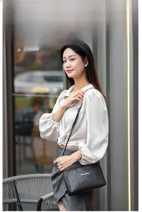Detail of black quilted shoulder bag with metal logo and sleek crossbody strap