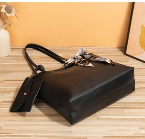 Détail d'un grand sac cabas noir en simili cuir avec un foulard en soie et une mini pochette
