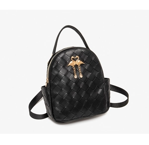 Detail of black mini backpack featuring woven PU leather texture and gold flamingo charm