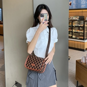 Bolso bandolera de cuadros marrones con logo metálico y correa ajustable en modelo