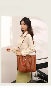 Brown leather tote bag featuring elegant patterned ribbon and adjustable shoulder straps