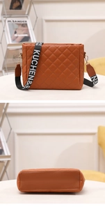 Close-up of brown quilted crossbody bag featuring a wide lettered strap and bottom detail