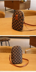 Close-up of a brown checkerboard crossbody mini phone bag with golden zipper detail