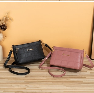 Detail of embossed faux leather crossbody bags in black and rose pink with gold hardware
