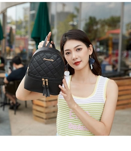 Détail d'un mini sac à dos noir matelassé avec doubles glands et finitions dorées