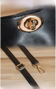 Détail du sac en cuir noir grainé avec fermoir doré et mousquetons métalliques réglables