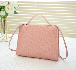 Detailed view of a pink woven texture crossbody bag with pearl handle and shoulder strap