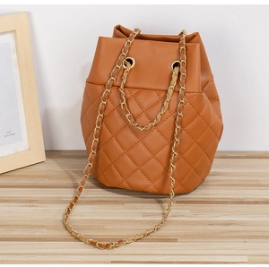 Gros plan détaillé du sac seau marron avec motif matelassé classique et bandoulière chaîne