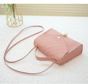 Detail of pink woven texture bag featuring pearl buckle and gold hardware accents