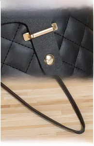 Detail of gold-plated buckle and quilted black leather texture on crossbody phone bag
