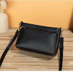 Close-up of black pebbled leather crossbody bag featuring luxury gold zipper hardware
