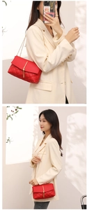 Détail du sac matelassé rouge avec finitions en pompon doré et bandoulière en chaîne