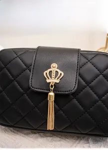 Close-up of black quilted leather lady bag featuring a gold crown tassel charm