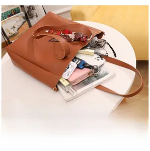 Internal storage view of caramel PU leather tote bag with daily essentials and silk scarf