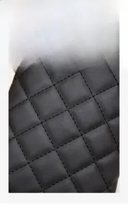 Close-up of black rhombic quilted fabric detailing on a stylish chain handbag