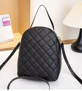 Detail of black quilted leather mini backpack with gold hardware on a marble surface