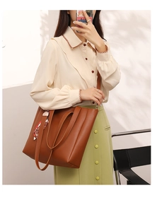 Brown leather tote bag with silk scarf detail worn as a crossbody by a model