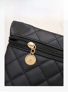 Detail of black quilted faux leather with gold circular zipper and stitching
