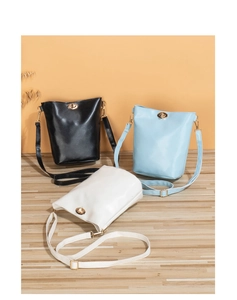 Trois sacs seaux minimalistes en noir, bleu clair et blanc avec fermoir tournant en métal