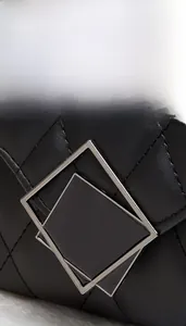 Detailed macro view of black quilted leather texture and silver square metal clasp